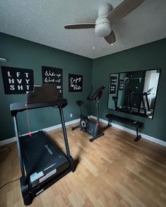 a home gym with treadmills, exercise equipment and mirrors on the wall above