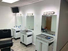 a hair salon with chairs, mirrors and lights