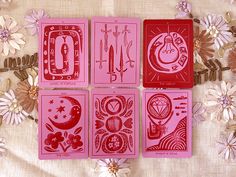 four pink playing cards sitting on top of a table next to white flowers and leaves