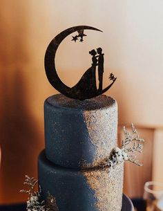 a wedding cake with a couple on top and the moon in the sky above it