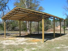 a covered area with trees and grass in the background