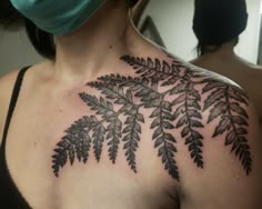 a woman wearing a surgical mask and covering her face with a tattoo on her chest