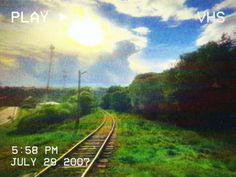 an image of a train track with the sun in the sky and clouds above it