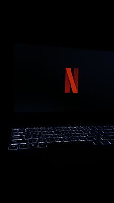 a laptop computer sitting on top of a black surface with the letter n in red
