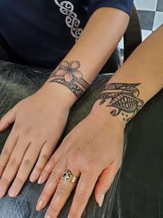 two hands with tattoos on them sitting next to each other