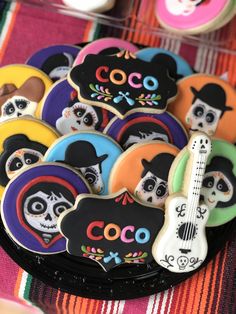 decorated sugar cookies in the shape of guitar and skull with name tags on them sitting on a colorful table cloth