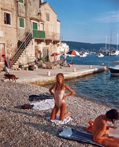 two people are sitting on the beach by the water