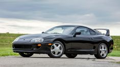 the black sports car is parked on the side of the road in front of some grass