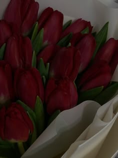 a bouquet of red tulips in a white paper wrapper