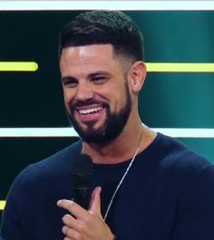 a smiling man holding a microphone in his hand