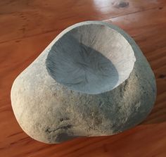 a stone bowl sitting on top of a wooden table next to a planter in the shape of a rock