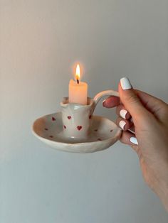 a person holding a tea cup with a lit candle in it and on a saucer