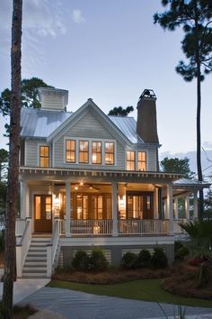 a large white house with lots of windows and lights on it's front porch