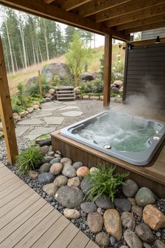 a hot tub sitting on top of a wooden deck next to rocks and grass covered ground