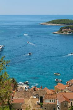 several boats are in the water near some buildings and trees, with an island in the background
