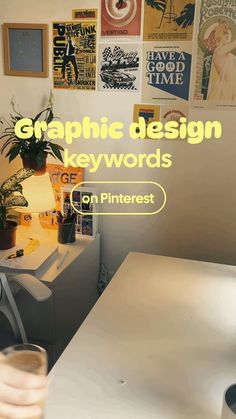 a white desk topped with a plant next to a wall covered in posters