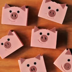 four pink pigs are sitting on top of some pieces of paper with holes in them