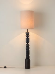 a lamp that is on top of a table next to a white wall and floor