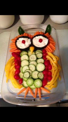 an owl made out of cucumbers, carrots and other vegetables on a tray