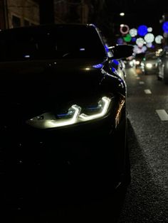 cars driving down the street at night with their headlights turned on and some lights on