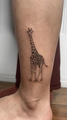 a small giraffe tattoo on the leg of a woman's lower body