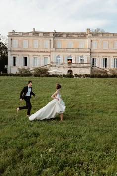 a bride and groom running in front of an old mansion