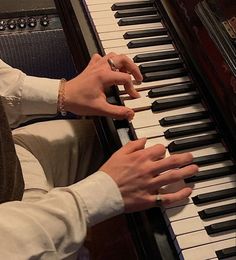 a man is playing the piano while wearing a ring on his left hand and holding it with both hands