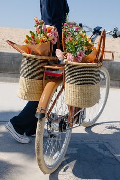 a person riding a bike with baskets full of flowers on the front and back wheels