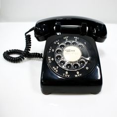 an old black telephone sitting on top of a white table