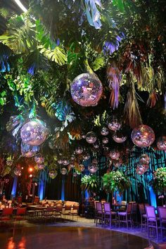 a room filled with lots of hanging disco ball lights and plants on the ceiling above