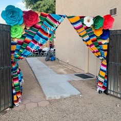 an archway decorated with colorful paper flowers and ribbons