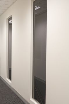 an empty room with three windows and carpeted flooring on the side of the wall