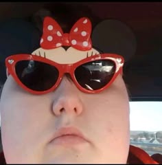 a woman wearing minnie mouse sunglasses with a bow on her head