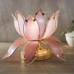 a pink and gold lotus sculpture on a wooden table