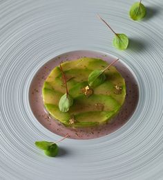 a white plate topped with an avocado covered in sauce and garnished with green leaves