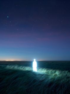 a person standing in the middle of a field at night