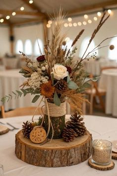 an arrangement of flowers in a vase on top of a tree stump at a wedding reception