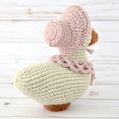 a crocheted duck sitting on top of a wooden floor next to a white wall