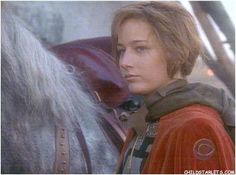 a woman standing next to a horse in front of a man wearing a red jacket