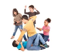 a group of kids sitting on the ground with their arms in the air and one boy holding a cell phone