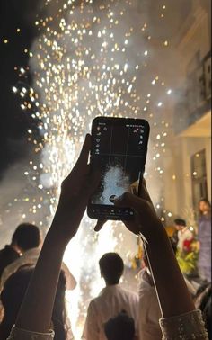 people are taking pictures with their cell phones as fireworks go off in the background