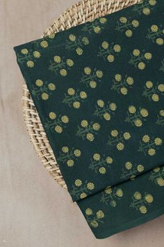two pieces of green fabric with gold pineapples on them sitting next to a wicker basket