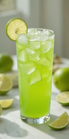 a glass filled with limeade and ice next to sliced limes on a table