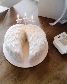 a cake with white frosting and lit candles on a plate next to a box