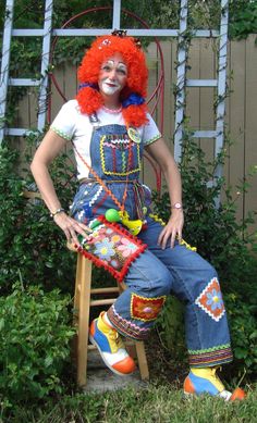 a clown is sitting on a chair in the yard