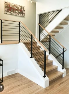 a stair case in a home with wood floors and metal railings on the bottom handrail