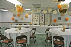 tables with white tablecloths and orange flowers on the wall in a banquet hall