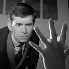 a man in a suit and tie holding his hand up