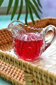 a glass pitcher filled with liquid sitting on top of a wicker tray