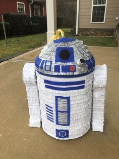 a star wars r2d2 paper mache sculpture on the sidewalk in front of a house
